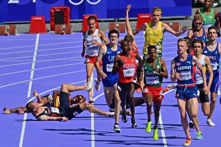 El español Thierry Ndikumwenayo y el británico George Mills (i) reaccionan después de una caída en la prueba masculina de 5000 m de atletismo en los Juegos Olímpicos de París 2024 en el Stade de France en Saint-Denis