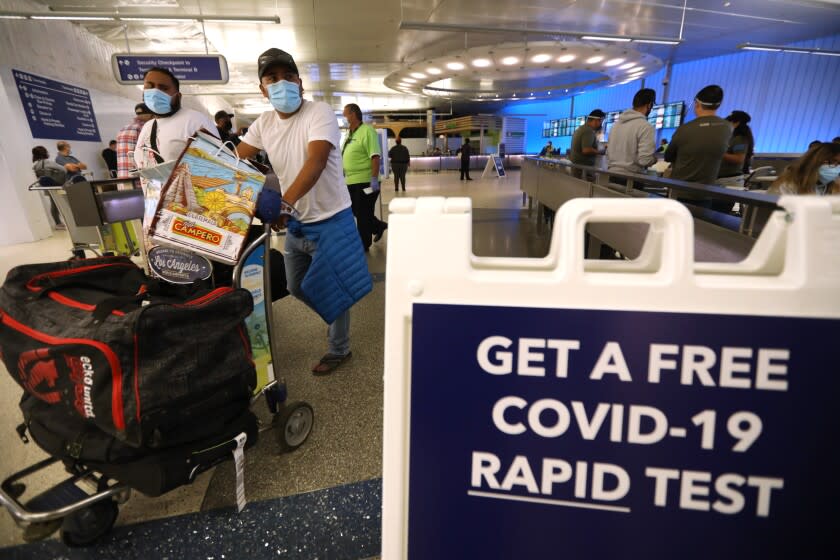 LOS ANGELES, CA - DECEMBER 3, 2021 - Arriving travelers walk past a sign directing them to get a free COVID-19 Rapid Test at the Tom Bradley International Terminal at Los Angeles International Airport Friday, December 3, 2021. In partnership with the state and U.S. Centers for Disease Control and Prevention, the county set up a free rapid testing site for arriving passengers. They were also gave those testing negative a kit they can use to test themselves again three to five days later, in line with CDC recommendations for international travelers coming to the U.S., regardless of vaccination status. Dr. Barbara Ferrer, director of L.A. County Department of Health, was on hand trying to direct arriving passengers to take a free COVID-19 test. (Genaro Molina / Los Angeles Times)