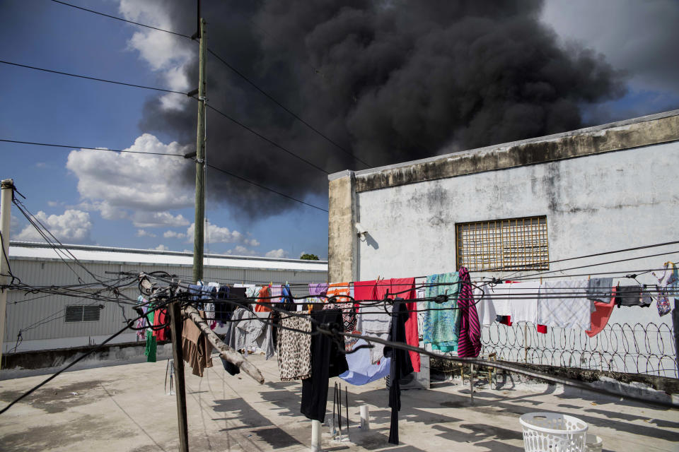 A black plume of smoke rises after an explosion at the Polyplas plant in the Villas Agricolas neighborhood in Santo Domingo, Dominican Republic, Wednesday, Dec. 5, 2018. The mayor told reporters the fire began when a boiler exploded early Wednesday afternoon at the plastics company. Authorities say at least two people have died. (AP Photo/Tatiana Fernandez)