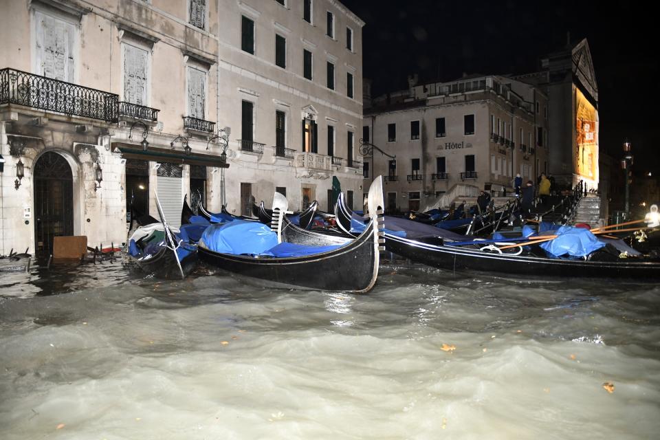 FILE - In this Wednesday, Nov. 13, 2019 file photo, stranded gondolas float adrift over the flooded banks, in Venice, Italy. Venice's hoteliers association estimates that the city's hotels suffered about 30 million euros ($34 million) worth of structural damage during November's floods. The overall losses though are higher when the lower revenues that local hotels have reported in the wake of the surging high tides are added in. (AP Photo/Luigi Costantini, File)