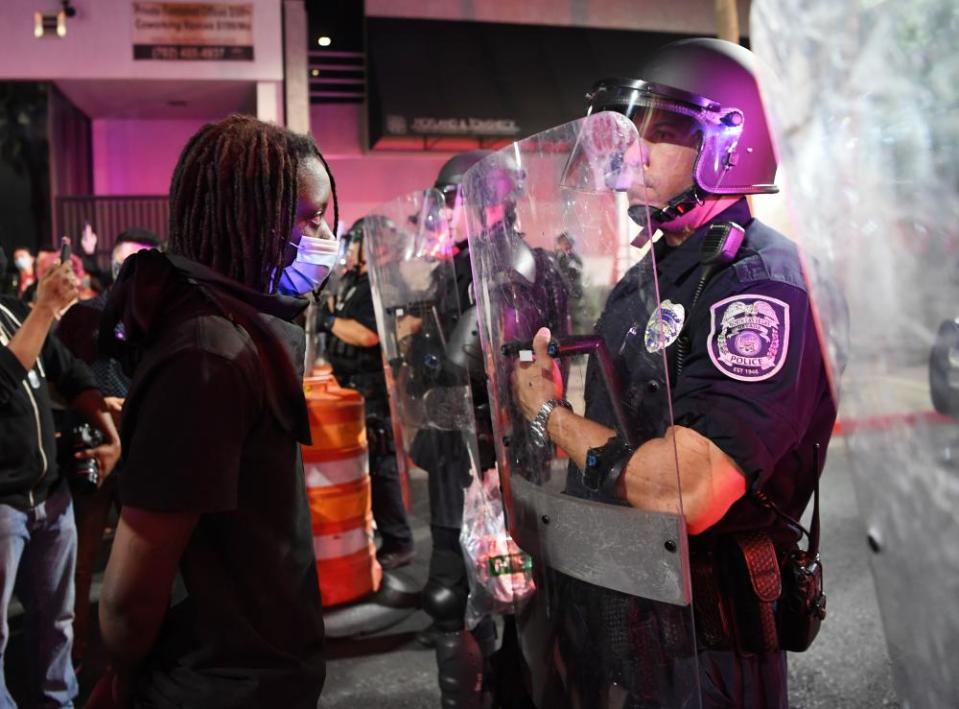 A protester in Las Vegas stands in front of a police officer during a demonstration demanding justice for the death of George Floyd.