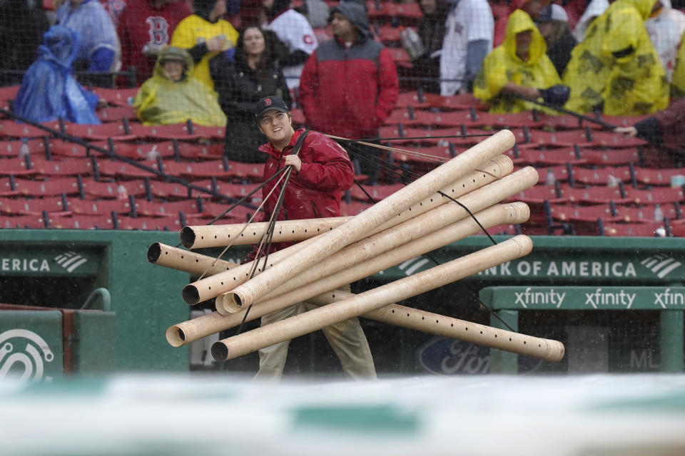 A grounds crew worker carries tubes onto the field during a rain delay of a baseball game against the Chicago White Sox, Sunday, Sept. 24, 2023, in Boston. (AP Photo/Steven Senne)