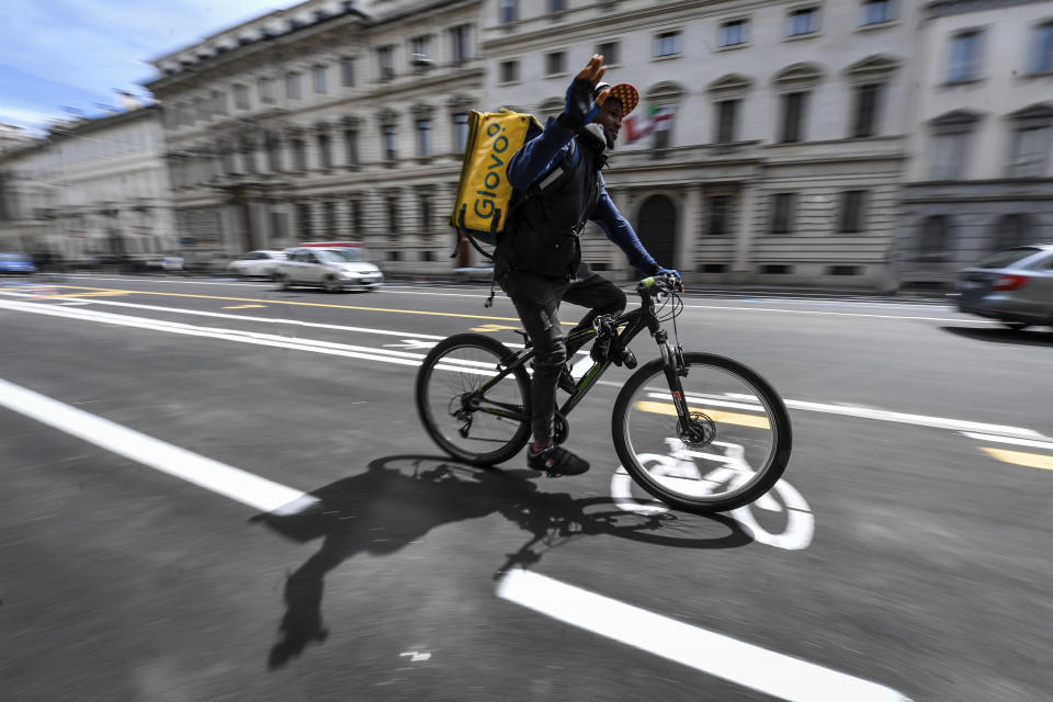 A delivery worker uses the new cycle path being prepared in central Milan's Corso Venezia, Italy, in view of Monday's partial reopening of activities, with a reduced capacity of public transportation due to safety measures against coronavirus, Saturday, May 2, 2020. Italians are preparing for the so called "phase 2" Monday, that will see a partial reopening of many activities after two months of lockdown due to the coronavirus outbreak. (Claudio Furlan/LaPresse via AP)