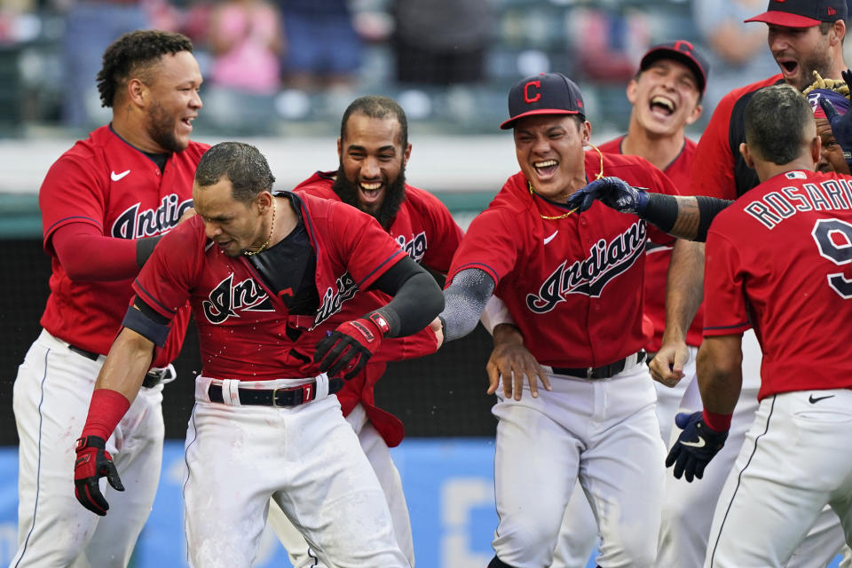 Teammates mob Cleveland Indians' Cesar Hernandez, second from left, after Hernandez hit a two-run home run in the 10th inning of a baseball game against the Minnesota Twins, Saturday, May 22, 2021, in Cleveland. (AP Photo/Tony Dejak)