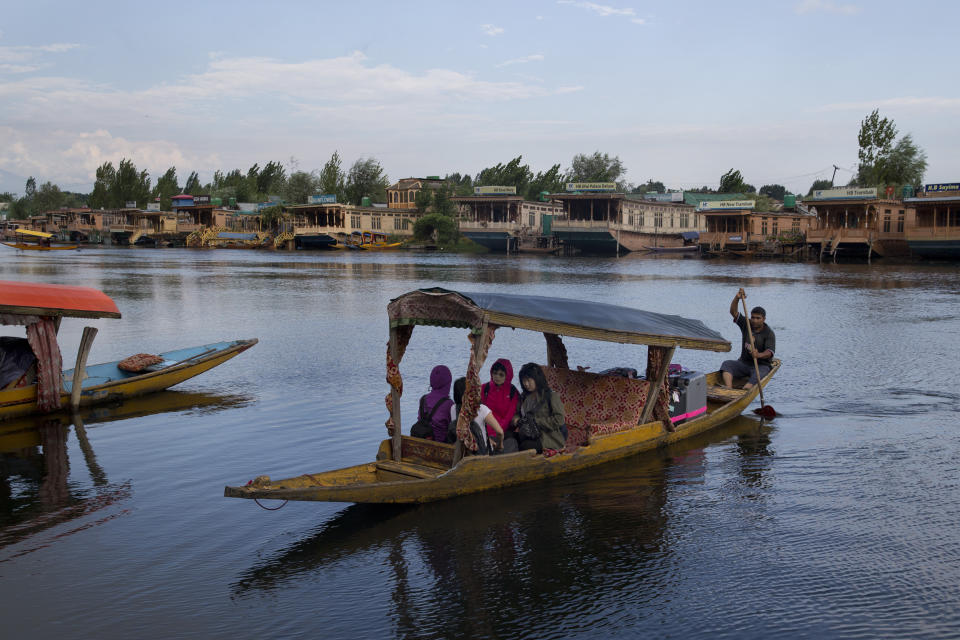 FILE - In this Saturday, Aug. 3, 2019, file photo, Foreign tourists cross the Dal Lake on a Shikara as they prepare to leave Srinagar, Indian controlled Kashmir. Authorities in Indian-controlled Kashmir are allowing tourists back into the region two months after ordering them to leave, citing security concerns. The local government had instructed tourists and Hindu pilgrims to leave on Aug. 2, three days before India stripped the Muslim-majority region of its statehood and special semi-autonomous status. (AP Photo/Dar Yasin, File)