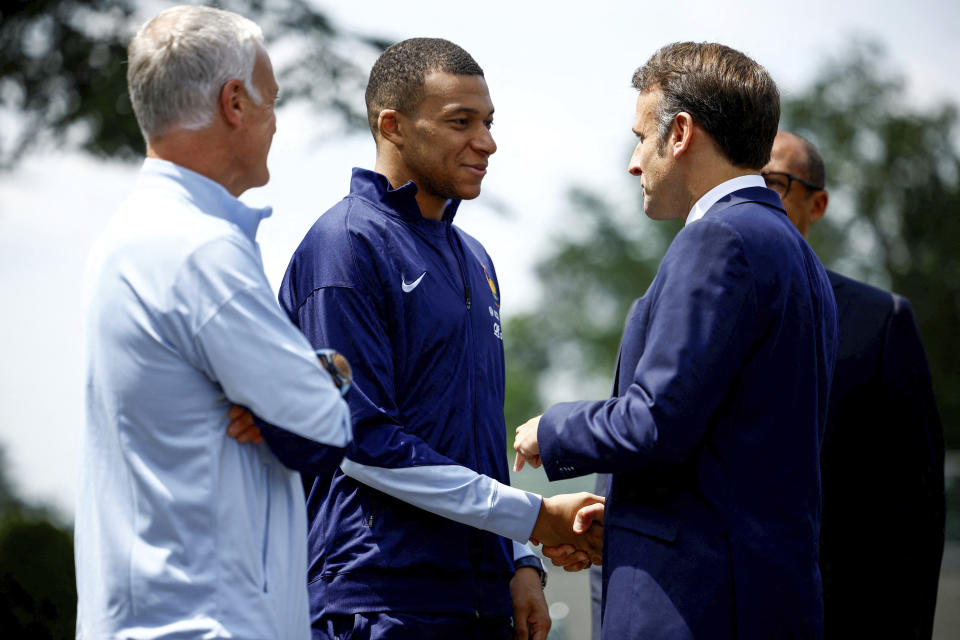 ARCHIVO - El presidente francés Emmanuel Macron (derecha) saluda al delantero francés Kylian Mbappé, al lado del técnico Didier Deschamps, previo a un encuentro en la ciudad deportiva de la selección nacional en Clairefontaine, el lunes 3 de junio de 2024. (Sarah Meyssonnier/Pool Foto vía AP)