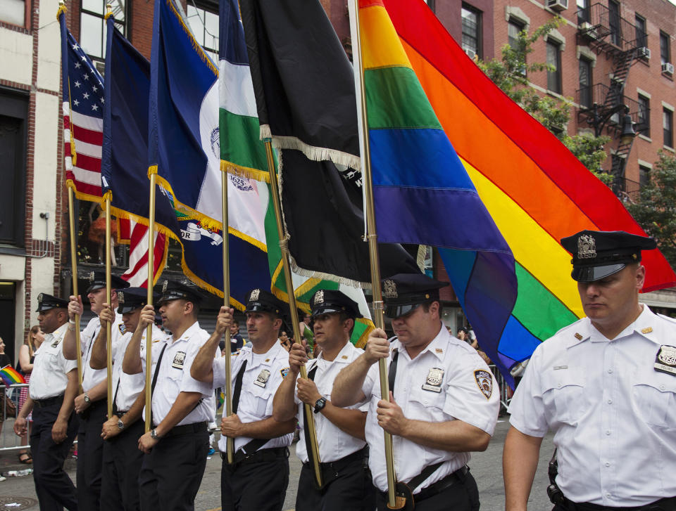 FILE - Members of the New York City Police Department carry flags, including one with the rainbow colors, during New York's Gay Pride Parade, June 30, 2013, in New York. As Pride weekend approaches, the recent decision by organizers of New York City's event to ban LGBTQ police officers from marching in future parades while wearing their uniforms has put a spotlight on issues of identity and belonging, power and marginalization. (AP Photo/Craig Ruttle, File)