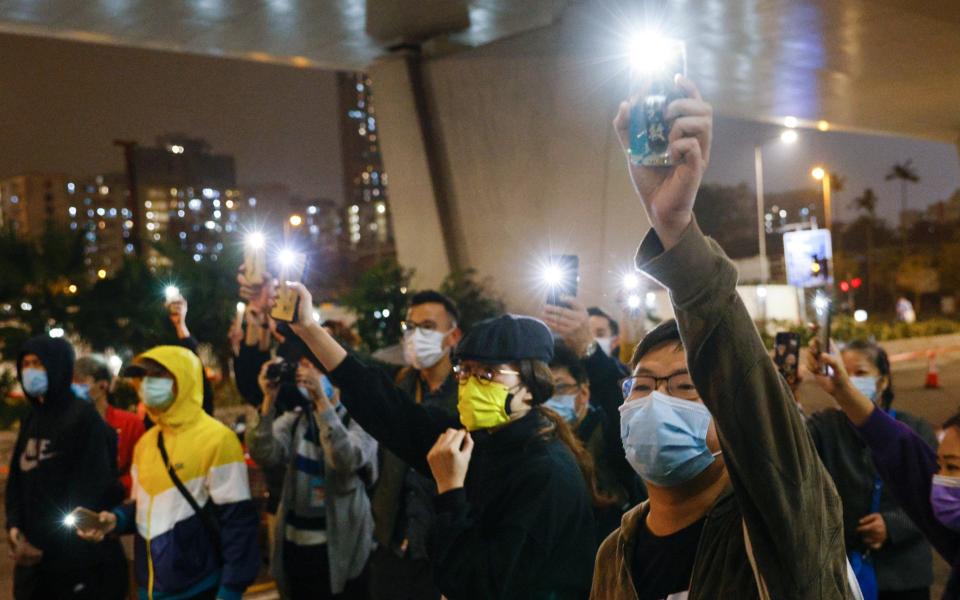 Supporters of 47 pro-democracy activists hold flashlights as they wait for four of them to leave the West Kowloon Magistrates Courts on bail - Tyrone Siu/Reuters