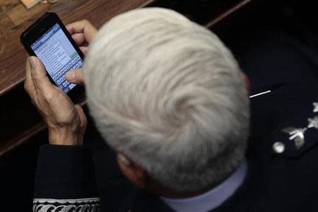 Brazilian Air Force Commander, Lieutenant-Brigadier Juniti Saito, writes a text message to an unidentified person named Araujo to celebrate the government's decision to purchase fighter aircraft from Sweden's Saab, as he attended a ceremony at the National Congress in Brasilia, December 18, 2013. REUTERS/Ueslei Marcelino