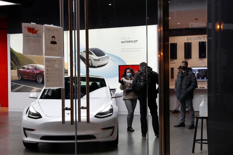 People wear protective face masks, as the global outbreak of the coronavirus disease (COVID-19) continues, inside a Tesla showroom in Chicago