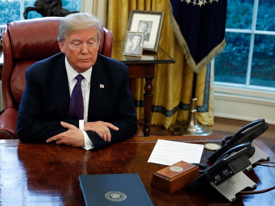 President Donald Trump sits at the Resolute Desk after signing Section 201 actions in the Oval Office of the White House in Washington, Tuesday, Jan. 23, 2018.