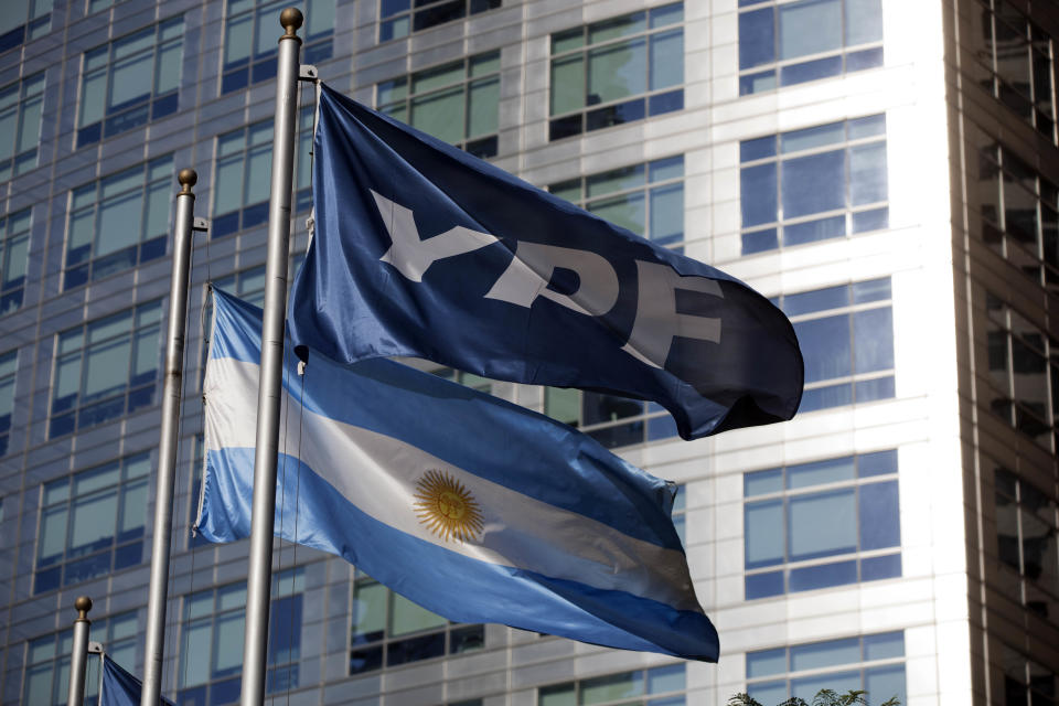 An Argentine flag, bottom, and a flag of the YPF oil company flutter in front of the YPF headquarters in Buenos Aires, Argentina, Monday, April 16, 2012. Argentine President Cristina Fernandez on Monday proposed a bill to expropriate 51 percent of the shares of YPF oil company that is controlled by Spain's Repsol, moving ahead with the plan despite fierce opposition from Madrid. (AP Photo/Natacha Pisarenko)