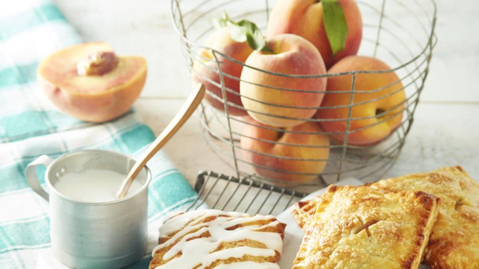 spiced peach hand pies drizzled with glaze and arranged on a wire rack