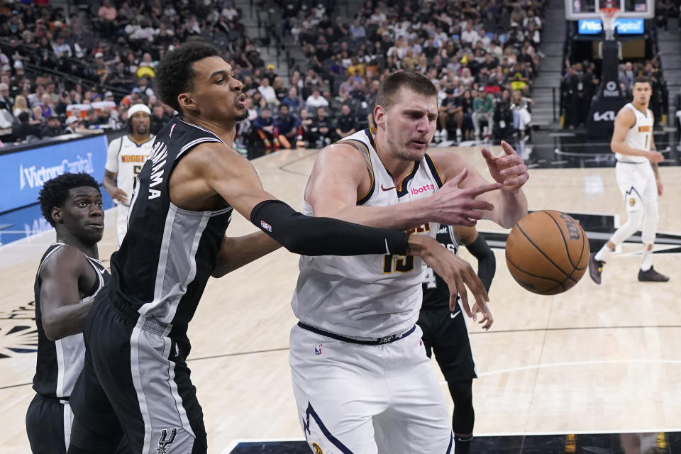 San Antonio Spurs center Victor Wembanyama, center, knocks the ball away from Denver Nuggets center Nikola Jokic (15) during the second half of an NBA basketball game in San Antonio, Friday, April 12, 2024. (AP Photo/Eric Gay)