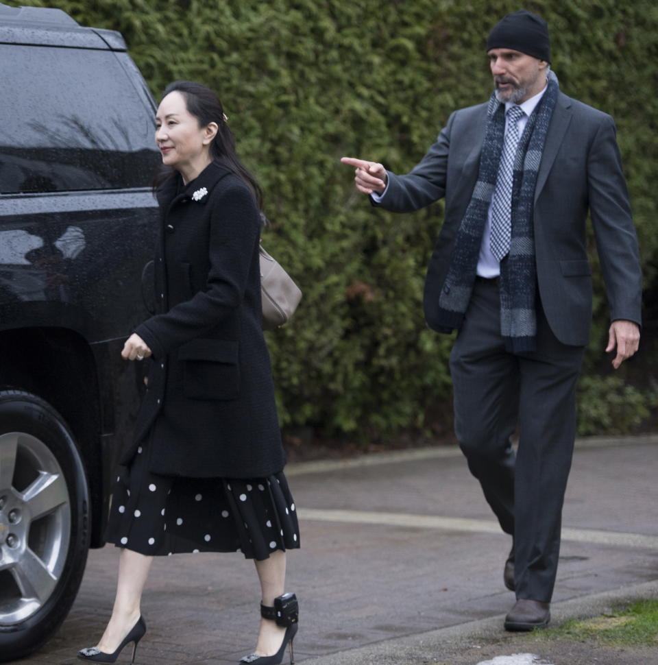 A security member points the way as Meng Wanzhou, chief financial officer of Huawei, leaves her home in Vancouver, Monday, January, 20, 2020. A court hearing begins today in Vancouver over the American request to extradite an executive of the Chinese telecom giant Huawei on fraud charges. (Jonathan Hayward/The Canadian Press via AP)