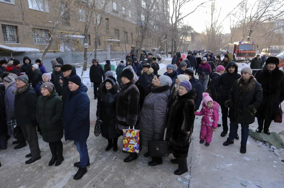 Locals gathered at the scene of the collapsed apartment building in Magnitogorsk, a city of 400,000 people, about 1,400 kilometers (870 miles) southeast of Moscow, Russia, Wednesday, Jan. 2, 2019. The building's pre-dawn collapse on Monday came after an explosion that was believed to have been caused by a gas leak. (AP Photo/Maxim Shmakov)