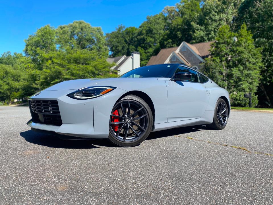 A gray 2024 Nissan Z Performance sports car is parked in front of homes.