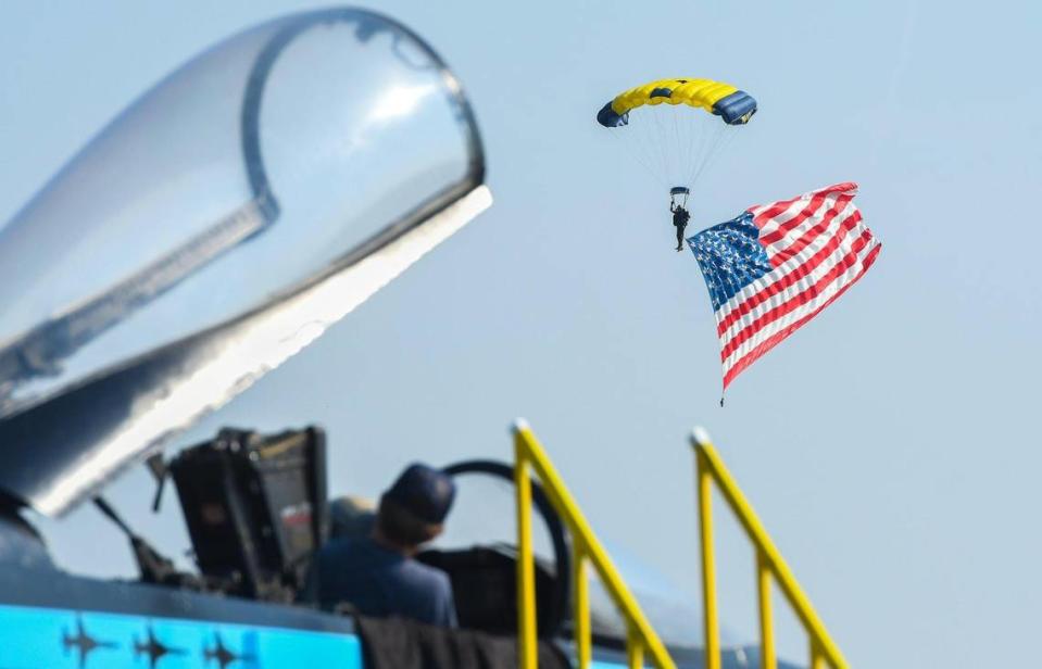 Spectators watch from the cockpit of a F-18 Hornet as a member of the Navy parachute team Leap Frogs arrives with an American flag during the national anthem on the second and final day of the 2021 Kansas City Airshow at the New Century AirCenter in New Century, Kansas, July 4, 2021.