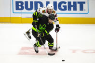 Dallas Stars center Andrew Cogliano (11) and Chicago Blackhawks left wing Alex DeBrincat (12) battle for the puck during the second period of an NHL hockey game, Sunday, Feb. 7, 2021, in Dallas. (AP Photo/Sam Hodde)