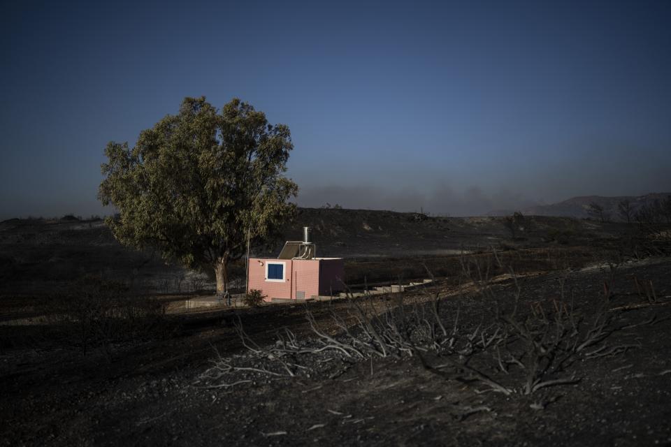 A house stands at a burnt forest near Gennadi village, on the Aegean Sea island of Rhodes, southeastern Greece, on Wednesday, July 26, 2023. A third successive heat has struck Greece, amid more evacuations from fires that have raged out of control for days, while the temperature in many parts of the country soaring Wednesday to as high as 46.4C (115 Fahrenheit). (AP Photo/Petros Giannakouris)