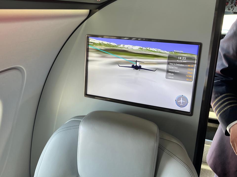 A screen shows a model airplane and journey information on board an Embraer Praetor 600