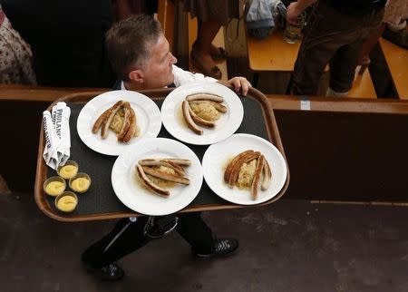 A waiter carries plates with sausages in a tent during the 182nd Oktoberfest in Munich, Germany, September 19, 2015. REUTERS/Michael Dalder/Files