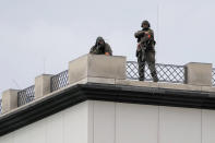 A police sharp shooter stands atop a building overlooking the Brandenburg Gate in Berlin, waiting for the arrival of Britain's King Charles III and Camilla, the Queen Consort, Wednesday, March 29, 2023. King Charles III arrived Wednesday for a three-day official visit to Germany. (AP Photo/Matthias Schrader)