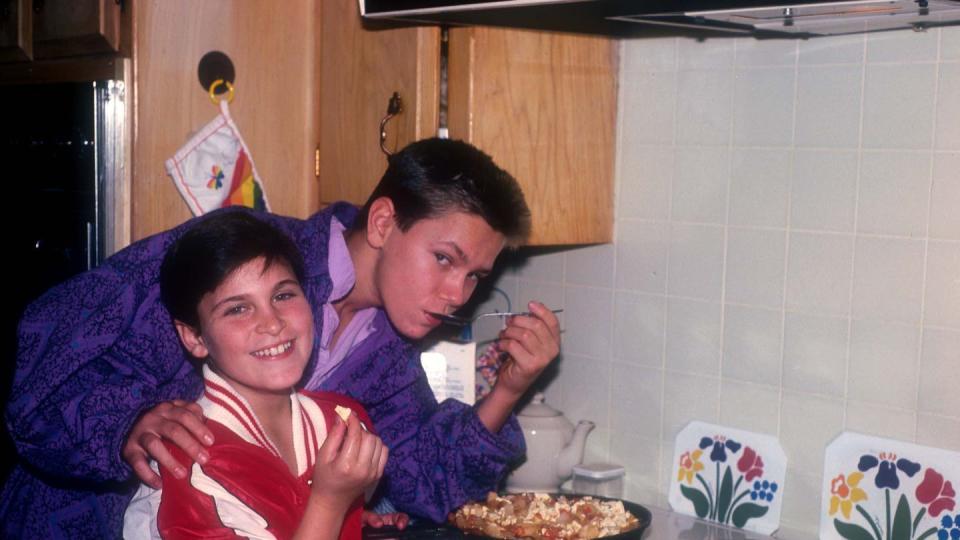 joaquin and river phoenix standing next to a stove cooking food and smiling for the camera