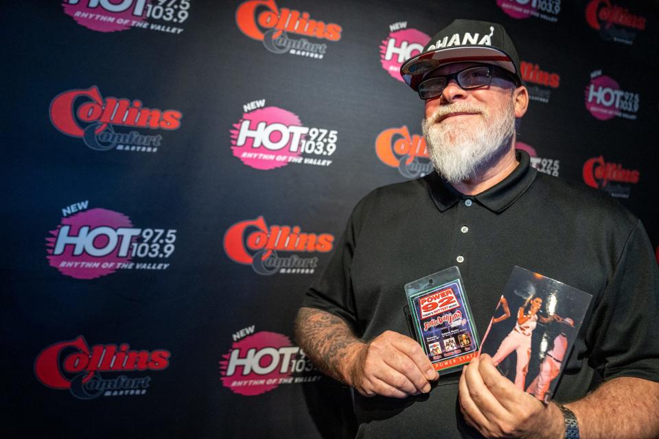 Charlie Huero, the assistant program director and afternoon host at HOT 97.5 & 103.9, poses for a portrait as he holds a 1999 staff credential and photograph of a Beyoncé and Destiny's Child performance at the Celebrity Theatre, at the radio station in Phoenix on Aug. 15, 2023.