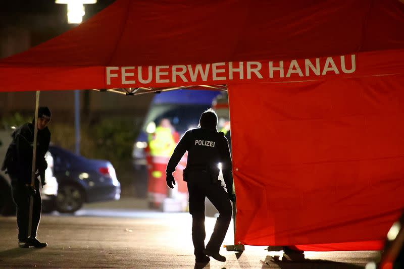 Police officers are seen walking by a tent with the words, "Fire Department Hanau" after a shooting in Hanau near Frankfurt