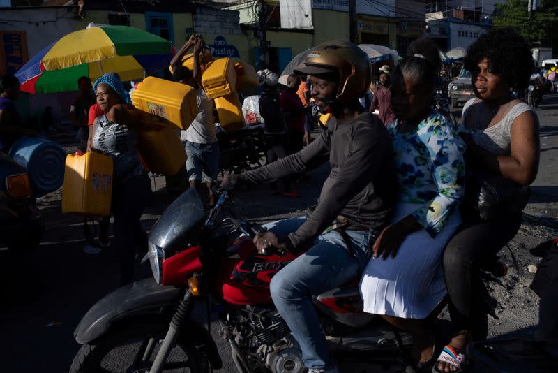 FILE PHOTO: Locals carry fuel containers in Port-au-Prince, Haiti