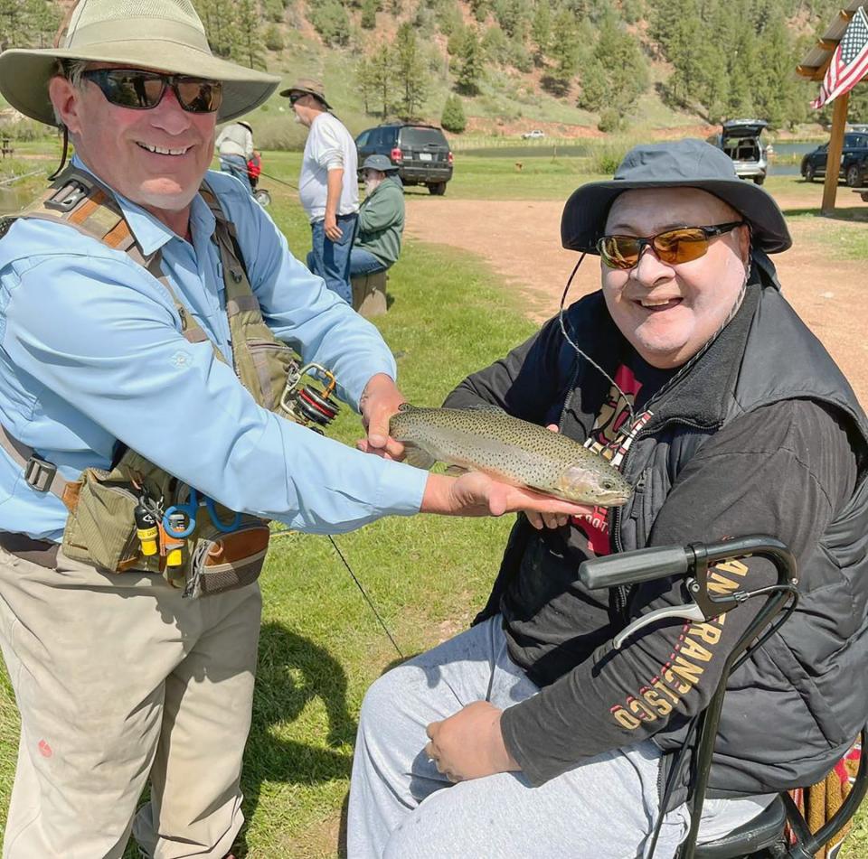 Alan Boatz (left) shows off the catch made by Richard, one of the vets from the Pueblo Veteran' Administration Community Living Center on June 7, 2023. In the background Ken Willard is working with another veteran.