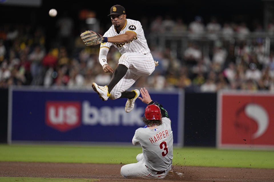 San Diego Padres shortstop Xander Bogaerts, throws to first for the double play as Philadelphia Phillies' Bryce Harper slides in late to second base during the fourth inning of a baseball game Tuesday, Sept. 5, 2023, in San Diego. Philadelphia Phillies' Alec Bohm was out at first on the play. (AP Photo/Gregory Bull)