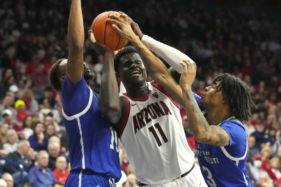 Arizona center Oumar Ballo (11) gets fouled, driving between Texas A&M Corpus Christi forward Isaac Mushila (10) and guard Tyrese Nickelson during the second half of an NCAA college basketball game, Tuesday, Dec. 13, 2022, in Tucson, Ariz. Arizona won 99-61. (AP Photo/Rick Scuteri)