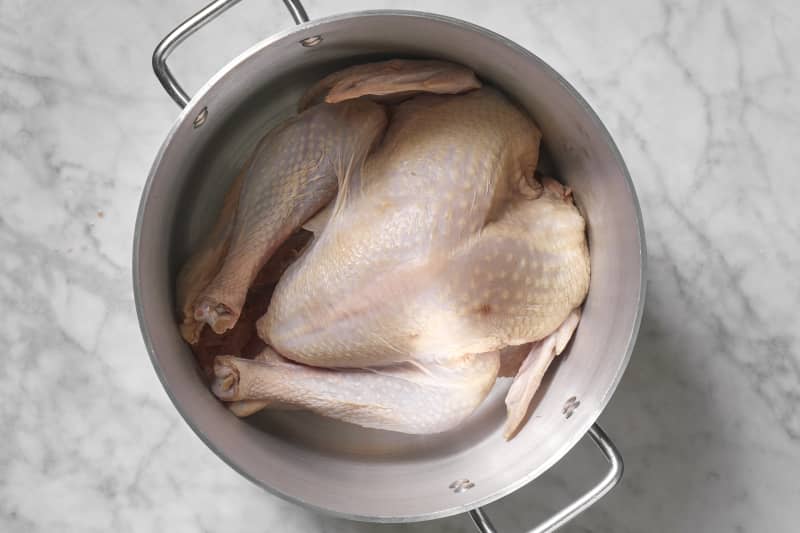 Overhead view of the raw turkey in a large silver pot.