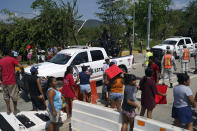 State police trucks and other security forces are present amid residents who took over the toll area of a road to demand water, food and help to rebuild their homes two days after Hurricane Otis hit as a Category 5 storm in Acapulco, Mexico, Friday, Oct. 27, 2023. (AP Photo/Marco Ugarte)