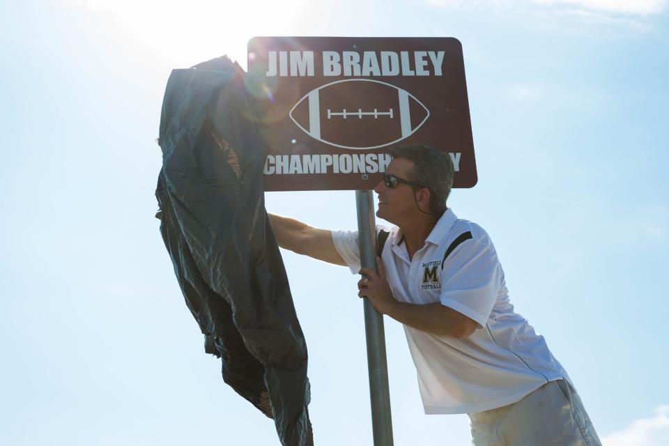 Michael Bradley, the head football coach at Mayfield High School, unveils one of the signs along Tashiro Road that now memorializes his late father, Jim Bradley, during a ceremony July 11, 2017.
