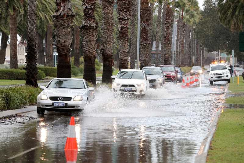 Cars navigate through floodwater on Riverside Drive in Perth CBD which is partially closed due to storm flooding.