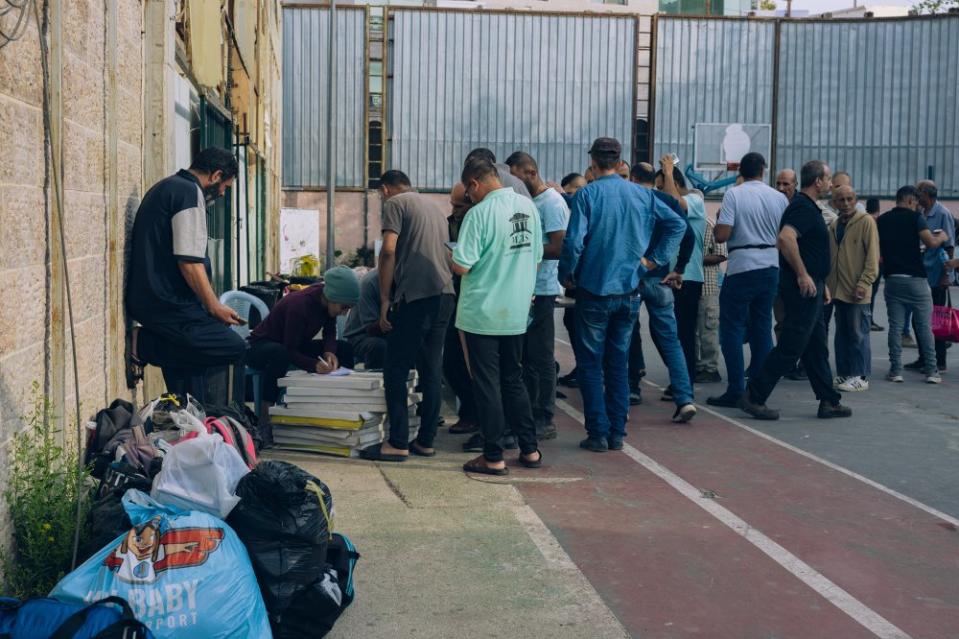 Palestinian workers from Gaza line up for registration at the Sarriyeh sports club in the West Bank city of Ramallah on Oct. 12. Over 400 Palestinians from Gaza sought refuge at the sports club in October, before being moved to another facility in the West Bank city of Jericho. Many of the workers arrived in buses after being taken from their work sites inside Israel. Some recounted being interrogated, beaten, blindfolded, and forced into the buses by Israeli police. Many others arrived on their own, entering the West Bank in secret, out of fear of being taken by Israeli police. <span class="copyright">Maen Hammad</span>