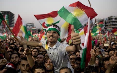 Supporters wave Kurdish flags in Erbil stadium as they wait to hear Kurdistan president Masoud Barzani - Credit: Getty