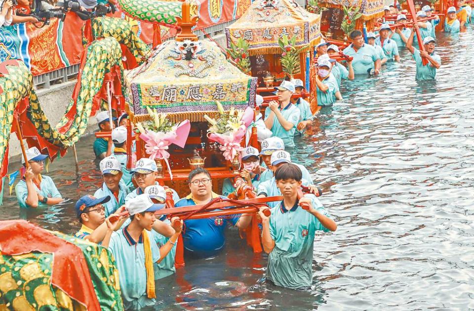 嘉義縣布袋鎮新塭嘉應廟5日舉辦一年一度「衝水路、迎客王」百年祭典，立委蔡易餘（扛轎中間著深藍衣）不畏溼身，親自下水體驗衝水路，熱情參與傳統祭儀。（呂妍庭攝）