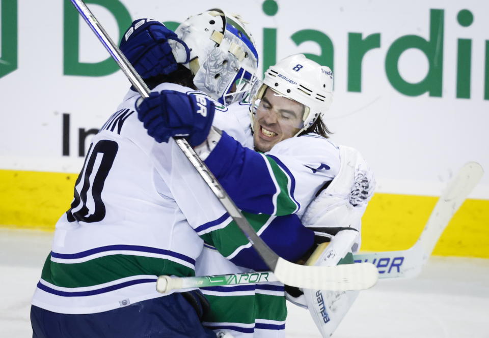 Vancouver Canucks goalie Spencer Martin, left, and forward Conor Garland celebrate defeating the Calgary Flames in a shootout during an NHL hockey game in Calgary, Alberta, Wednesday, Dec. 14, 2022. (Jeff McIntosh/The Canadian Press via AP)