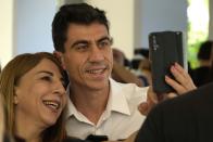 A woman takes a selfie with popular YouTuber and TikToker with millions of online followers Fidias Panayiotou after his proclamation as the winner of one of six seats allotted to Cyprus in the European Parliament at the Filoxenia Conference Center in the capital Nicosia, Cyprus, on Tuesday, June 11, 2024. The 24-year-old Cypriot says he will continue using social media in his new job as a member of the European Parliament because he sees it as "my biggest weapon to use" in affecting the kind of change he wants to see on issues such as education. (AP Photo/Petros Karadjias)