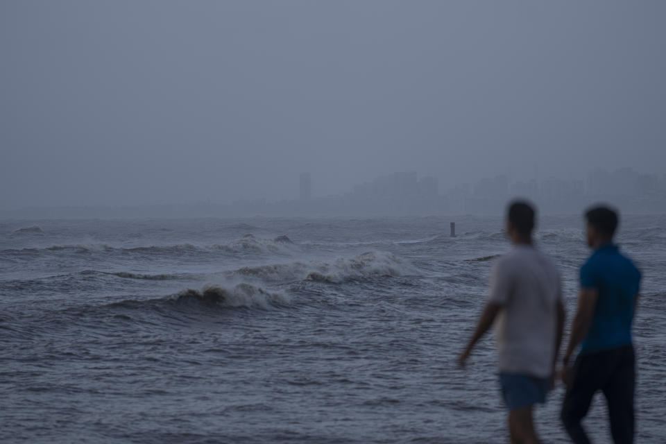 People watch as high tide waves hit the Arabian Sea coast at Juhu Koliwada in Mumbai, India, Monday, June 12, 2023. Cyclone Biparjoy, the first severe cyclone in the Arabian Sea this year is set to hit the coastlines of India and Pakistan Thursday. (AP Photo/Rafiq Maqbool)