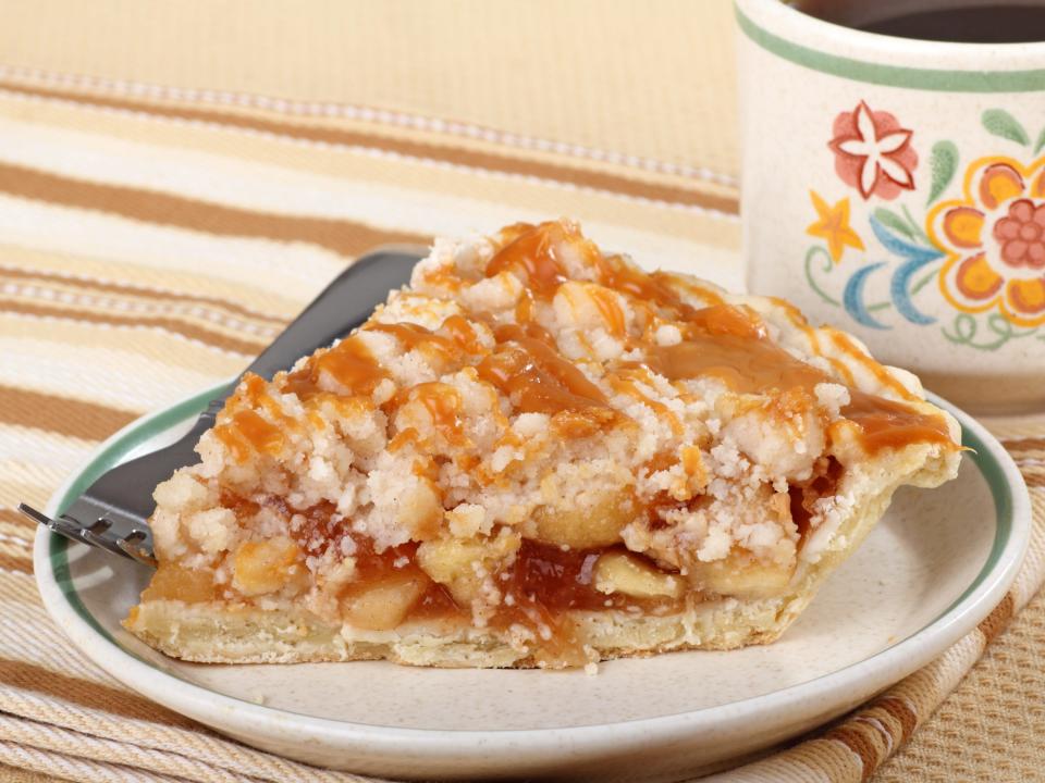 Apple Pie on a white plate with a form and mug by it