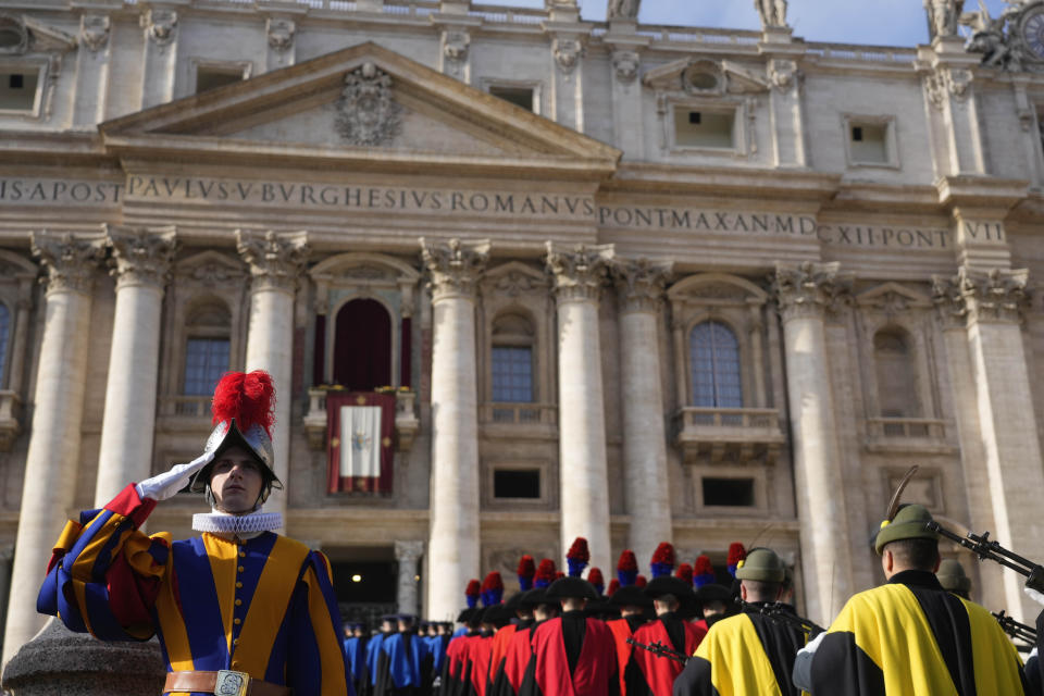 A Swiss guard salute members of the Italian army marching towards the St.Peter's Basilica prior to the start of Pope Francis Urbi et Orbi (Latin for 'to the city and to the world' ) Christmas' day blessing at the Vatican, Sunday, Dec. 25, 2022. (AP Photo/Gregorio Borgia)