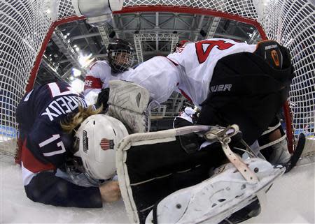 Team USA's Jocelyne Lamoureux (17) crashes into Switzerland's goalie Florence Schelling (R) as Switzerland's Laura Benz defends during the third period of their women's preliminary round hockey game at the Sochi 2014 Winter Olympic Games February 10, 2014. REUTERS/Martin Rose/Pool