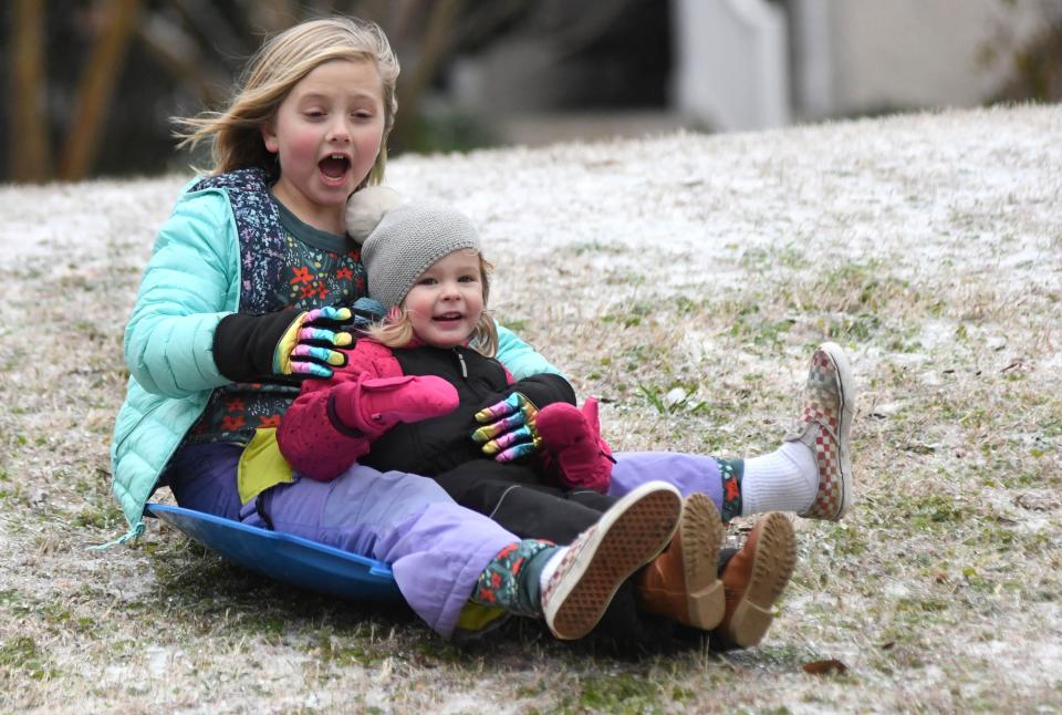 Hattie Kennedy, 7, and Annie Cooper, 2, sled down the ice at Wallace Park in Wilmington, N.C., Saturday Jan. 22, 2022. A wintry mix fell throughout the night over the Wilmington area and created dangerous conditions.   [MATT BORN/STARNEWS]   