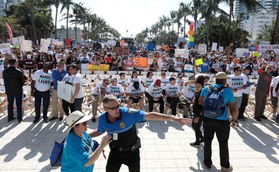 People stand while rallying in the street during the March For Our Lives demonstration, demanding stricter gun control laws, at the Miami Beach Senior High School.