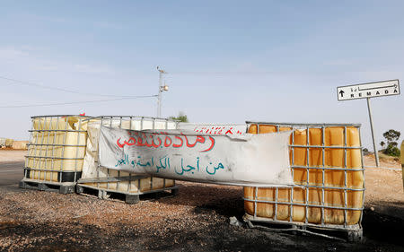 A sign is seen at the edge of Remada, Tunisia October 11, 2018. Picture taken October 11, 2018. A sign reads: "Remada, you shall rise for dignity and bread". REUTERS/Zoubeir Souissi